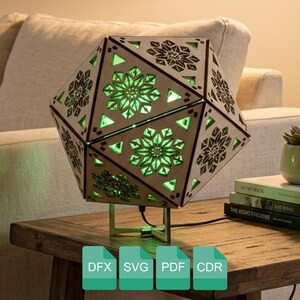 May include: Geometric wooden lamp with intricate floral and geometric cutouts, illuminated by a soft green glow. The lamp sits on a wooden table, showcasing its unique design. The lamp is a decorative lighting fixture.