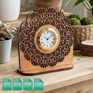 Puede incluir: Reloj de escritorio de madera con diseño de mandala cortado con láser. La esfera del reloj es blanca con números romanos negros y ribete dorado. El reloj está hecho de madera marrón claro y tiene una base rectangular. La imagen también muestra iconos de tipo de archivo: DFX, SVG, PDF y CDR.