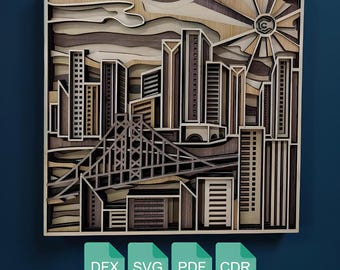 May include: A layered wooden art piece depicting a cityscape with skyscrapers, a bridge, and a sun. The artwork is made of various shades of brown wood, creating a 3D effect. The bottom of the image shows the text "DFX SVG PDF CDR".