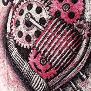 May include: Close-up of a detailed embroidered design featuring a heart shape composed of gears and mechanical components. The heart is primarily pink and black, with white accents. The design has a steampunk aesthetic.