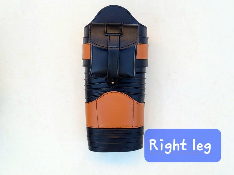 May include: A black and tan leather leg protector with a pocket and straps. The product has a rectangular shape with a rounded top and is labeled "Right leg" in a blue box.