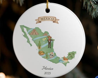 May include: A circular white ceramic Christmas decoration depicting a map of Mexico with illustrations of landmarks and a person in traditional dress. The word "Mexico" is on a banner, and "Mexico 2025" is written below the map.