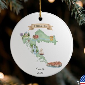 Può includere: Ornamento natalizio in ceramica bianca con una mappa ad acquerello della Croazia e dei suoi monumenti. La parola "Croatia" è visualizzata su uno striscione. Il testo "Croatia 2025" è stampato sotto. Un cordino dorato è attaccato per appenderlo.