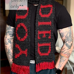 May include: A black crochet scarf with the word "DOOMED" in red letters. The scarf has red fringe at the bottom and the text "pattern only" in a white box in the upper left corner.