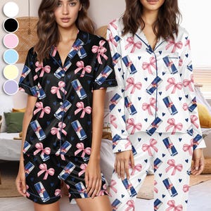 Puede incluir: Dos conjuntos de pijama de sat&eacute;n. Un conjunto es negro con un estampado de lazos rosas, corazones azules y latas de Red Bull. El otro conjunto es blanco con el mismo estampado. Ambos conjuntos tienen ribetes azules.