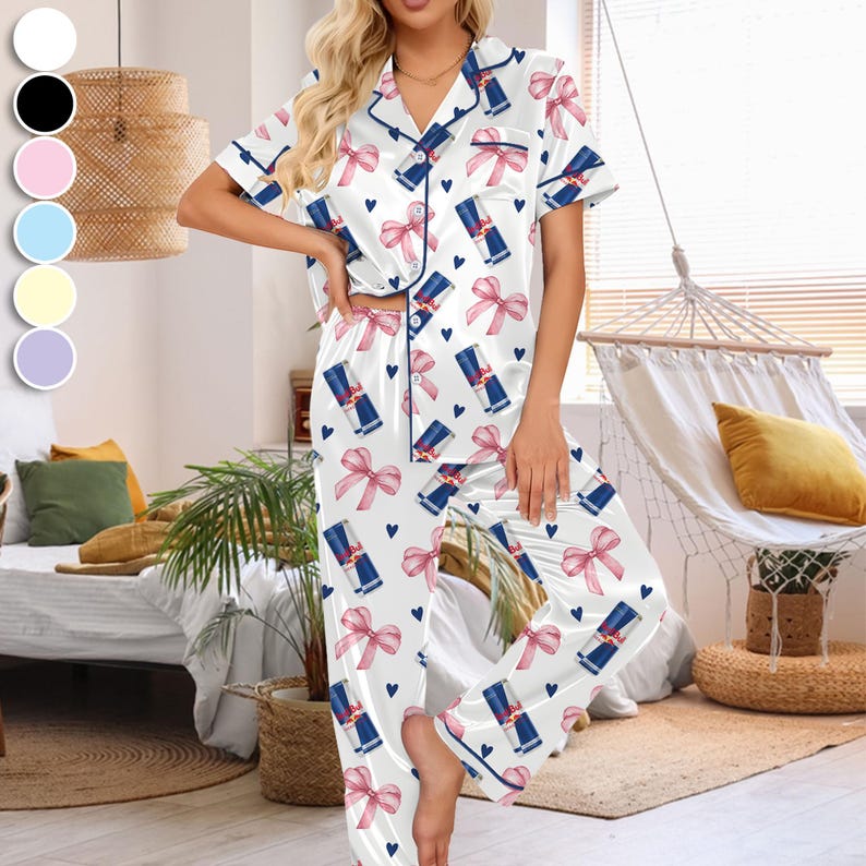 Puede incluir: Conjunto de pijama de sat&eacute;n blanco con un estampado de lazos rosas, corazones azules y latas de Red Bull. La parte superior de manga corta y los pantalones tienen ribetes azul marino. Dise&ntilde;ado para la comodidad y la relajaci&oacute;n.