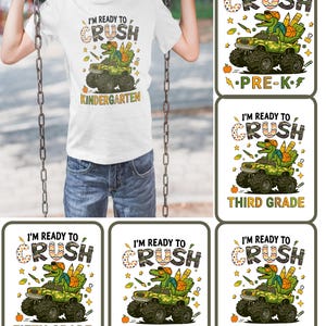 Peut inclure: T-shirt blanc avec un motif d'un dinosaure vert conduisant un monster truck, avec le texte "I'M READY TO CRUSH" et "KINDERGARTEN". D'autres images montrent le même motif avec "PRE-K", "THIRD GRADE", "FIFTH GRADE", "FIRST GRADE", et "FOURTH GRADE".