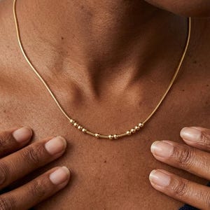 May include: A white ceramic mug with a black handle and the text "But First, Coffee" in a bold, black font. The mug is likely 325 ml in size and sits on a white surface.