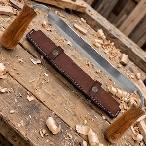 May include: A drawknife featuring a long, sharp metal blade with two wooden handles on either side. The tool includes a dark brown leather sheath with two metal snap buttons, designed to cover the blade for safe storage and protection.
