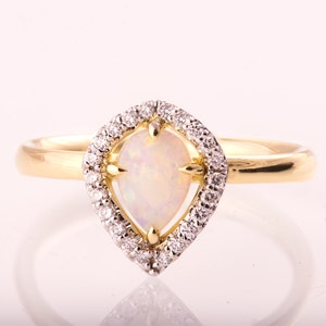 Puede incluir: Un anillo de oro con una opala en forma de pera engastada en un halo de peque&ntilde;os diamantes.