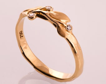 May include: A gold band ring with a delicate leaf design and three small diamonds. The ring is marked "150" on the inside.