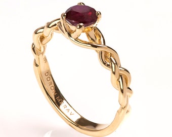 May include: A gold ring with a braided band and a red ruby gemstone. The ring is engraved with the words "DORON MERAV".