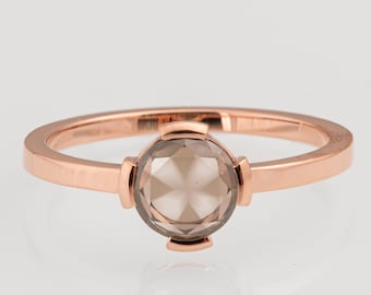Op de afbeelding: Een ring van roségoud met een ronde, gefacetteerde, lichtbruine edelsteen.