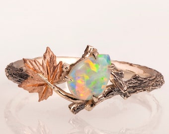 May include: A gold ring with a branch and leaf design. The ring features a pear-shaped opal gemstone.