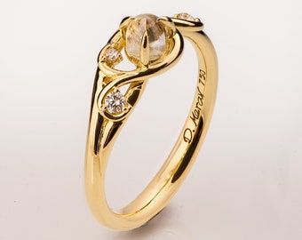 Könnte beinhalten: Ein goldener Ring mit einem klaren Edelstein und kleineren Diamanten, die in einem filigranen, ineinander verschlungenen Design gesetzt sind. Der Ring ist mit "D. Meray 750" graviert.