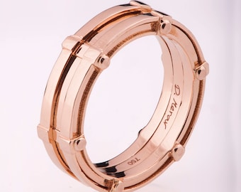 May include: A rose gold band ring with a geometric design and the inscription "D. Keren" and "T. 180".