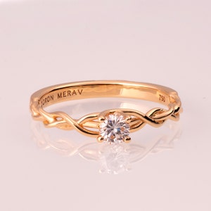 K&ouml;nnte beinhalten: Ein goldener Ring mit geflochtenem Design und einem einzelnen runden Diamanten in der Mitte. Der Ring ist mit "DORON MERAV 750" graviert.