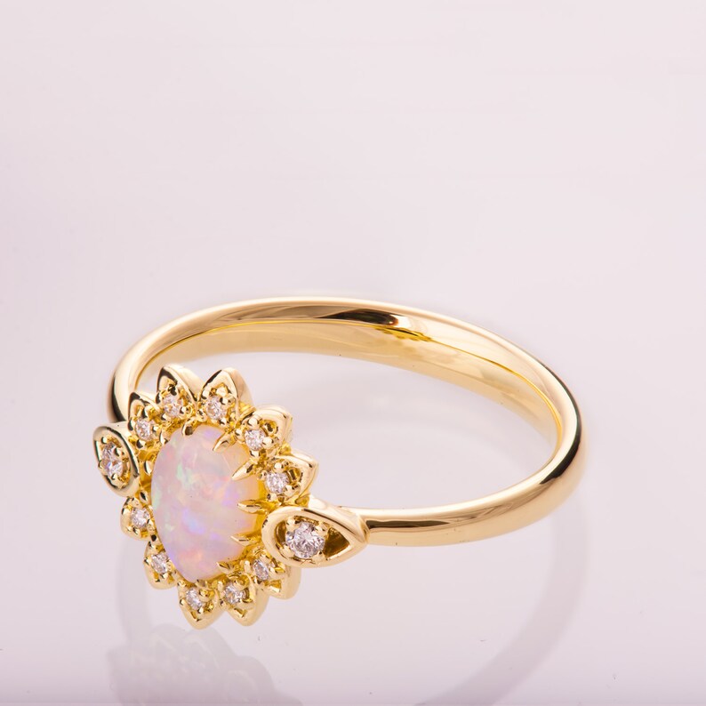May include: A gold ring with a white opal gemstone surrounded by a halo of small diamonds.