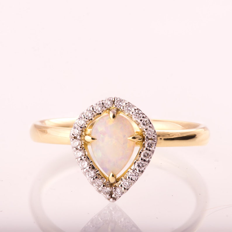 Puede incluir: Un anillo de oro con una opala en forma de pera engastada en un halo de peque&ntilde;os diamantes.