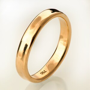 May include: A simple gold wedding band with a smooth, rounded surface. The band is marked with the number "750" on the inside.
