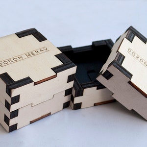 May include: Three wooden boxes with black trim and the text "DORON MERAV" engraved on the top. The boxes are stacked on top of each other.