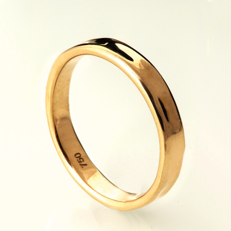 May include: A simple gold wedding band with a smooth, rounded surface. The band is marked with the number "750" on the inside.