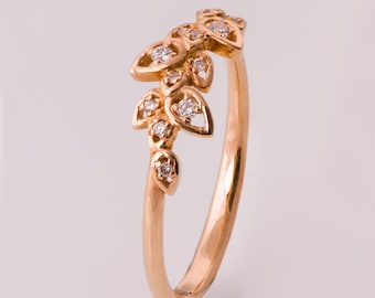 May include: A delicate gold ring featuring a leaf design with small diamonds. The ring is a simple band with a row of leaves and diamonds on the top.