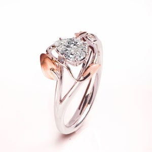 May include: A silver and rose gold ring featuring a large pear-shaped diamond set within a delicate, leafy design.