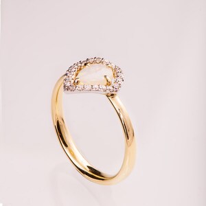Puede incluir: Un anillo de oro con una piedra de &oacute;palo en forma de pera rodeada por un halo de peque&ntilde;os diamantes.