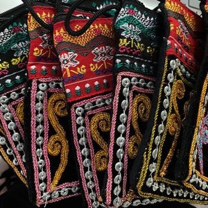 May include: A set of six small, black fabric pouches with colourful embroidery and silver sequins. The pouches have a variety of designs, including floral patterns, geometric shapes, and abstract designs.