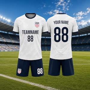 May include: White soccer jersey and shorts set with navy blue accents. The jersey features the USA emblem, team name, and the number 88. The shorts also display the number 88. The background shows a soccer field and stadium.