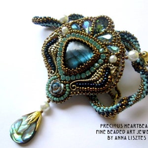 May include: A beaded pendant featuring a central triangular labradorite stone, surrounded by bronze, teal, and black seed beads, white pearls, and a dangling iridescent shell teardrop. Text reads: PRECIOUS HEARTBEADS FINE BEADED ART JEWELRY BY ANNA LISZTES.