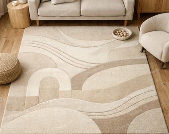 Puede incluir: Una alfombra rectangular beige y marrón con un diseño abstracto de líneas curvas y formas geométricas. La alfombra está colocada sobre un suelo de madera y tiene una superficie texturizada. La paleta de colores incluye crema, beige y marrón.