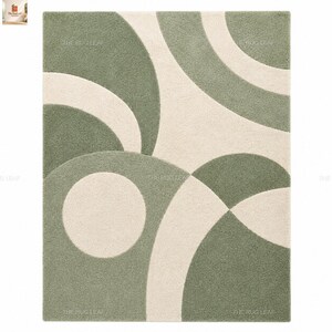 May include: A rectangular area rug featuring a high-pile texture with a geometric pattern of sage green and cream-coloured curved shapes and circles. The design consists of overlapping arcs and circular forms that create a balanced composition.
