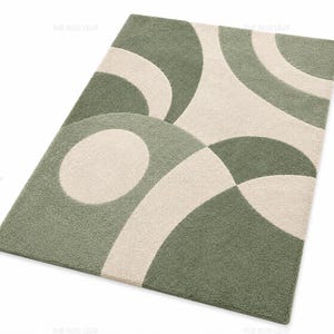 May include: A rectangular area rug featuring a tufted texture with a geometric pattern of overlapping sage green and cream-coloured circles and arcs. The design consists of curved shapes that create a repeating abstract motif across the surface.