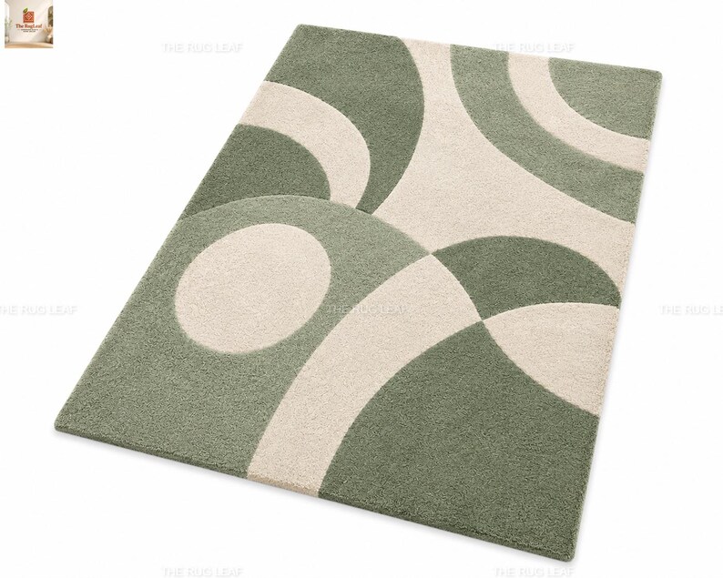 May include: A rectangular area rug featuring a tufted texture with a geometric pattern of overlapping sage green and cream-coloured circles and arcs. The design consists of curved shapes that create a repeating abstract motif across the surface.