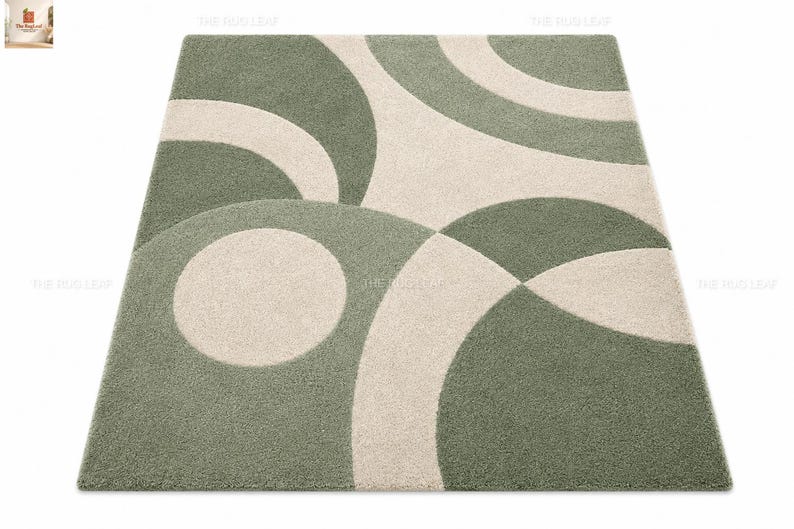May include: A rectangular area rug featuring a geometric pattern of overlapping circles and arcs in sage green and cream. The rug has a dense, textured pile surface with clean, curved lines that create a repeating abstract design across the entire piece.