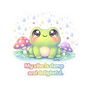 May include: A sticker featuring a cute green frog with large, expressive eyes, sitting between two mushrooms. Raindrops, hearts, and stars surround the frog. The text "My vibe is damp and delightful" is written in a rainbow gradient.