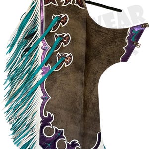 May include: Brown leather chaps with intricate tooling and decorative accents. Features include turquoise fringe, purple trim, and white stitching. The chaps have a western-style design with a buckle closure and decorative leather ties.