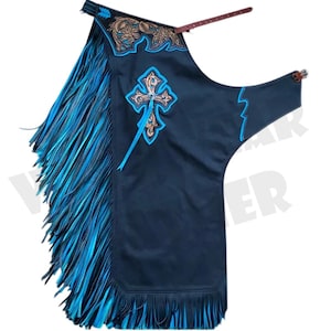 Puede incluir: Chaps de cuero azul marino oscuro con flecos y detalles turquesa. Presenta un diseño de cruz con bordados turquesa y dorados. Incluye cinturón de cuero marrón y cierre de hebilla. Ropa del oeste.