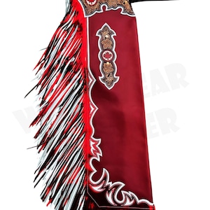 Puede incluir: Chaps de cuero rojo con flecos blancos y negros. Los chaps tienen costuras decorativas y un diseño de hoja de arce. Diseñados para montar a caballo, tienen una correa para sujetarlos.