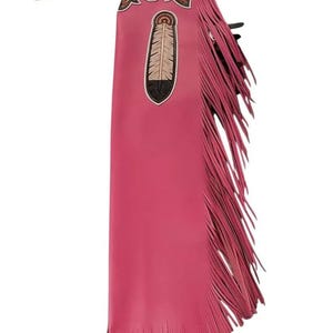 May include: Pink leather chaps with a decorative feather design and fringe. The top portion features a brown and gold floral pattern. The chaps are designed to be worn over pants for horseback riding or rodeo events.