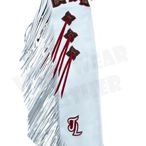 May include: White leather chaps with silver fringe and decorative red and brown floral accents. The chaps feature red star-shaped designs and a red embroidered initial. A brown leather belt is attached at the top.