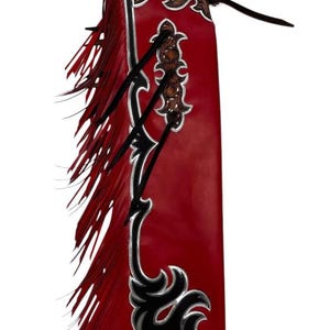 Puede incluir: Chaps de cuero rojo con detalles decorativos negros y plateados. Los chaps presentan flecos en el lateral y un intrincado labrado en la parte superior y central. Una prenda de estilo western.