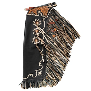 May include: Black leather chaps with intricate floral and scrollwork embroidery. The chaps feature long, layered fringe in shades of brown, tan, and black. A decorative leather belt and buckle secure the chaps at the waist. The chaps are designed for riding.