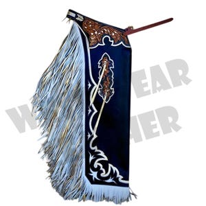 May include: A single black leather chaps with white and gold fringe. The chaps feature brown floral tooling and white decorative stitching. A brown leather strap extends from the top.
