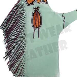 Puede incluir: Chaps de cuero verde claro con flecos decorativos y bordados florales. Los chaps tienen una correa de cuero marrón y un parche decorativo con un diseño de plumas naranja y marrón.