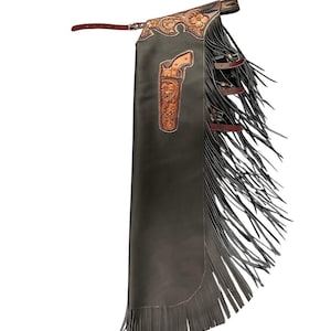 Puede incluir: Chaps de cuero negro con detalles y flecos de cuero marrón. Los chaps presentan un diseño de cuero labrado con una funda y motivos florales. Los chaps tienen cinturón y cierre de hebilla.