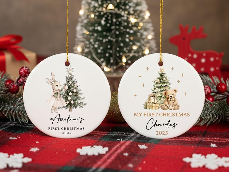 May include: Two white ceramic Christmas ornaments with gold hanging strings. One features a bunny with a Christmas tree, the text "Amelia's FIRST CHRISTMAS 2025". The other has a teddy bear, tree, gifts, and the text "MY FIRST CHRISTMAS Charles 2025".