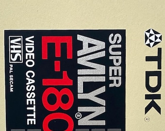 May include: A vintage TDK Super Avilyn E-180 VHS video cassette. The label features the text "HIGH OUTPUT HIGH RESOLUTION", "VIDEO CASSETTE", and "180 min. of video recording and playback". The cassette has a beige background with black, red, green, and blue accents.